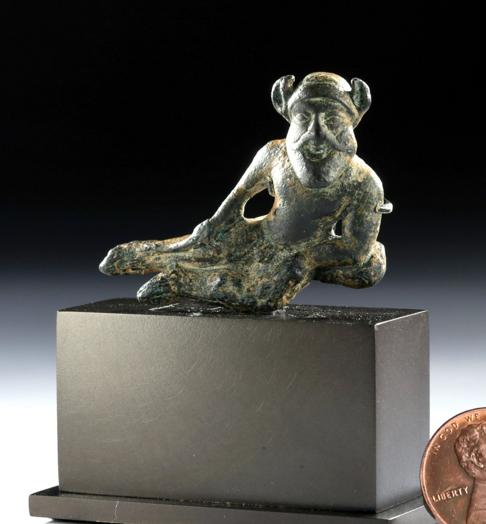Rare Miniature Etruscan Bronze Reclining Satyr Applique: Etruria, northern Italy, ca. 6th to 5th century BCE. A solid bronze statuette, finely cast via the lost wax (cire perdue) process, depicting a satyr - possibly Silenus - reclining on a lion's skin. Th