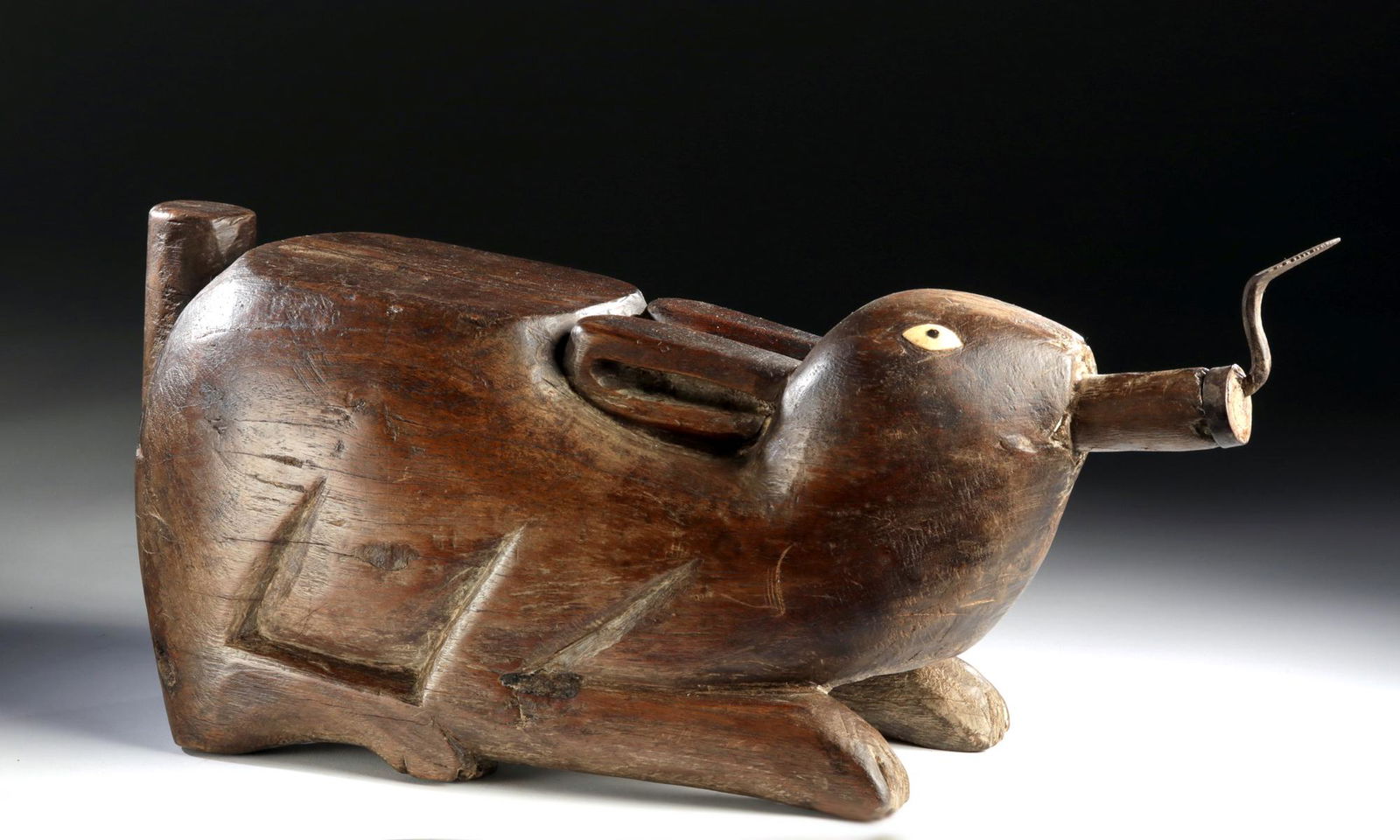 19th C. Thai Wood Coconut Grater - Rabbit: Southeast Asia, Thailand or Cambodia, ca. late 19th to early 20th century CE. A hand-carved wooden coconut grater depicting an adorable recumbent rabbit. The bunny rests atop a quartet of retracted le