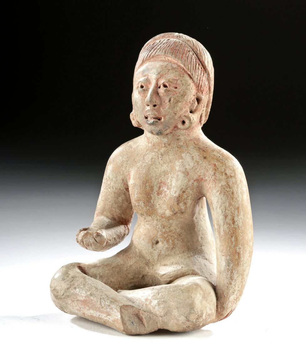 Olmecoid / Proto-Maya Pottery Seated Female Figure: Pre-Columbian, Southern Mexico to Guatemala, Olmec to Proto-Maya culture, ca. 500 BCE to 300 CE. A hand-built pottery female figure seated upon slender, crossed legs. The nude woman holds one arm to h