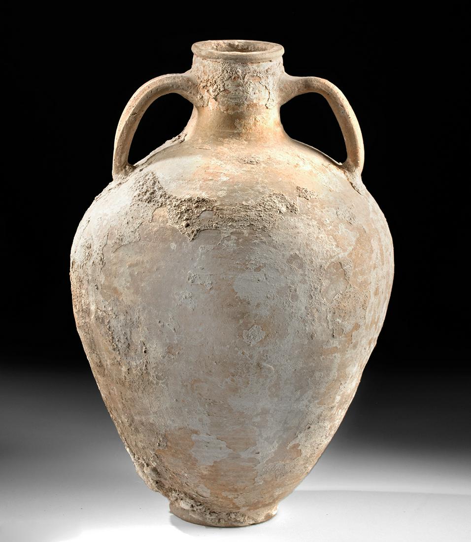 Sea Salvaged Roman Pottery Transport Amphora: Roman, Imperial Period, ca. late 2nd to 3rd century CE. A sizable buffware pottery transport amphora with a circular base, inverted piriform body, a rounded shoulder that tapers to a squat, cylindrica