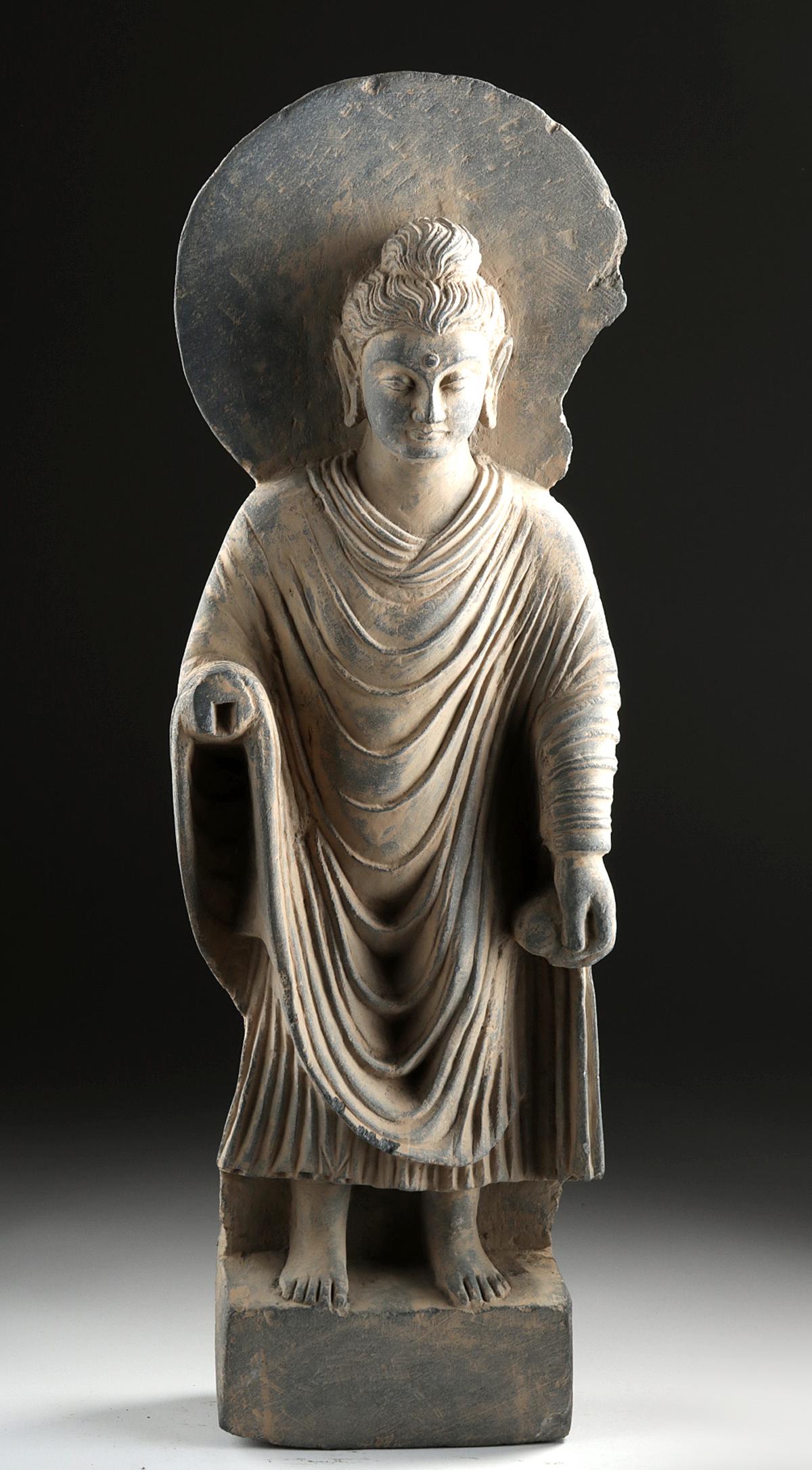 Tall Gandharan Schist Sculpture - Standing Buddha: Ancient Central Asia, Pakistan, India, and Afghanistan, Gandharan Empire, ca. 1st to 2nd century CE. A large and naturalistic carving from the period of Greco-Buddhist art, Buddha shown in a standing 