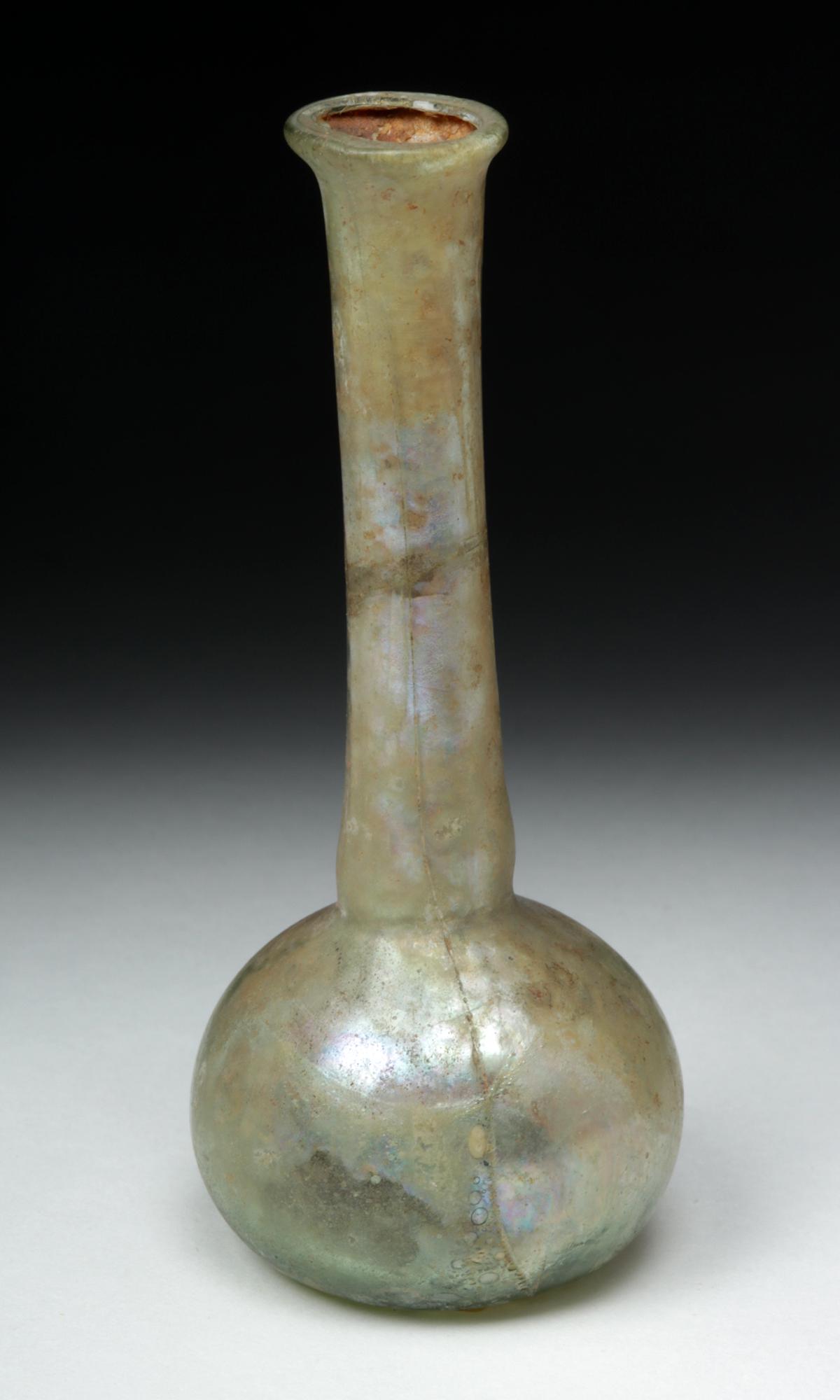 Roman Glass Unguentarium: **First Time At Auction** Roman, Imperial Period, ca. 1st to 3rd century CE. A beautiful free-blown unguentarium (or perfume bottle), fashioned from a pale-green glass, with a thin overall composition