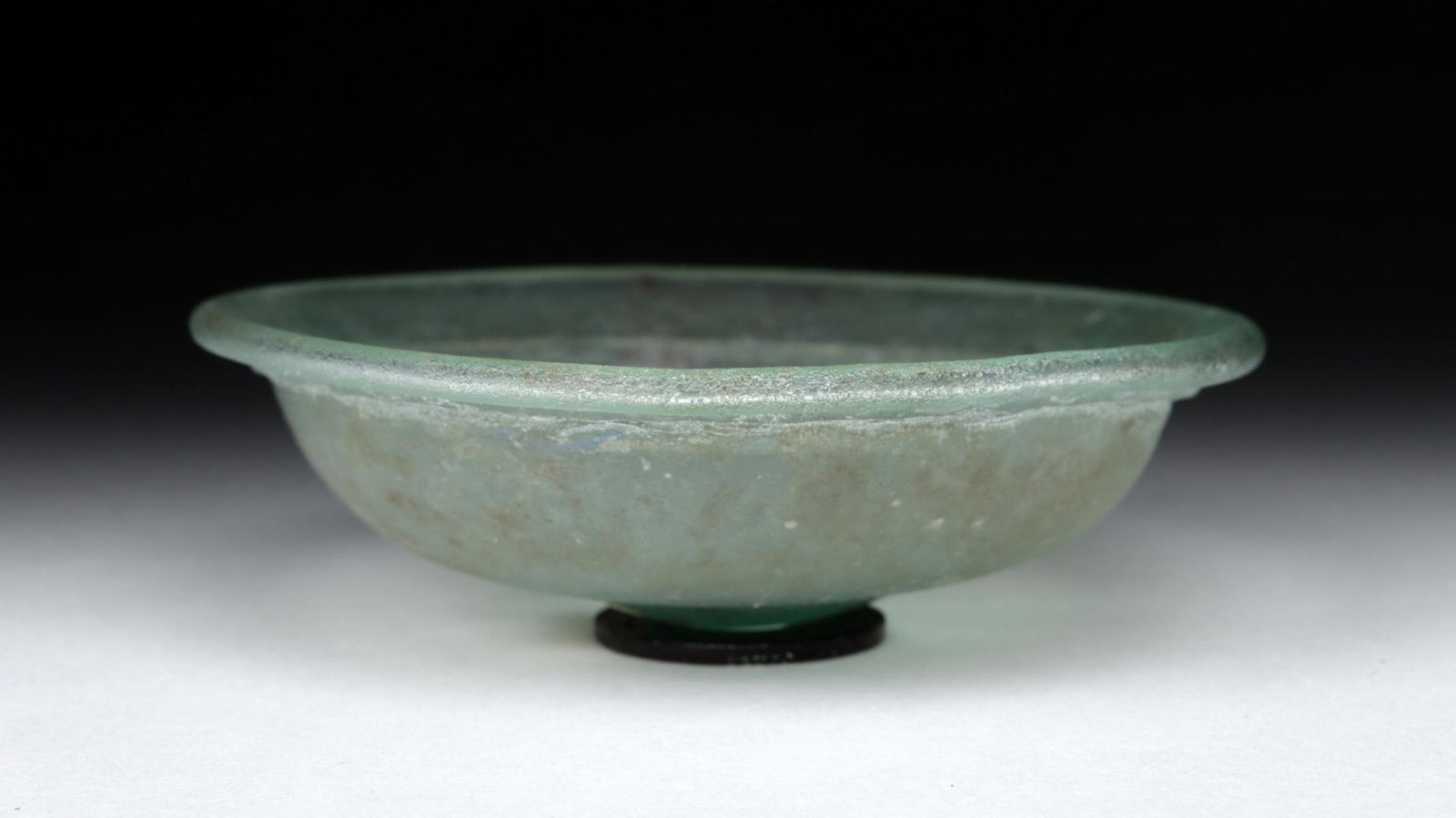 Unusual Roman Glass Lid: **First Time At Auction** Roman, early Imperial period, ca. 1st to 2nd century CE. A pretty glass lid from a jar, made from pale blue glass. With a slightly flared rim and a small bump forming a handl