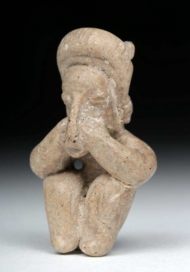 Cute Jalisco Pottery Miniature Seated Figural Pendant: **First Time At Auction** Pre-Columbian, Western Mexico, Jalisco, ca. 300 BCE to 300 CE. A hand-built miniature pottery figure with large legs, bent arms, and a slender torso. Both arms reach up to a 