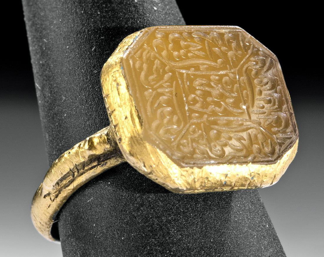Medieval Islamic 20K Gold Ring w/ Glass Intaglio: Middle East, Islamic world, ca. 1000 to 1500 CE. A beautiful 20K gold ring with a thick shank, a pair of stocky shoulders, and an octagonal face set with a hand-carved glass intaglio of warm citrine h