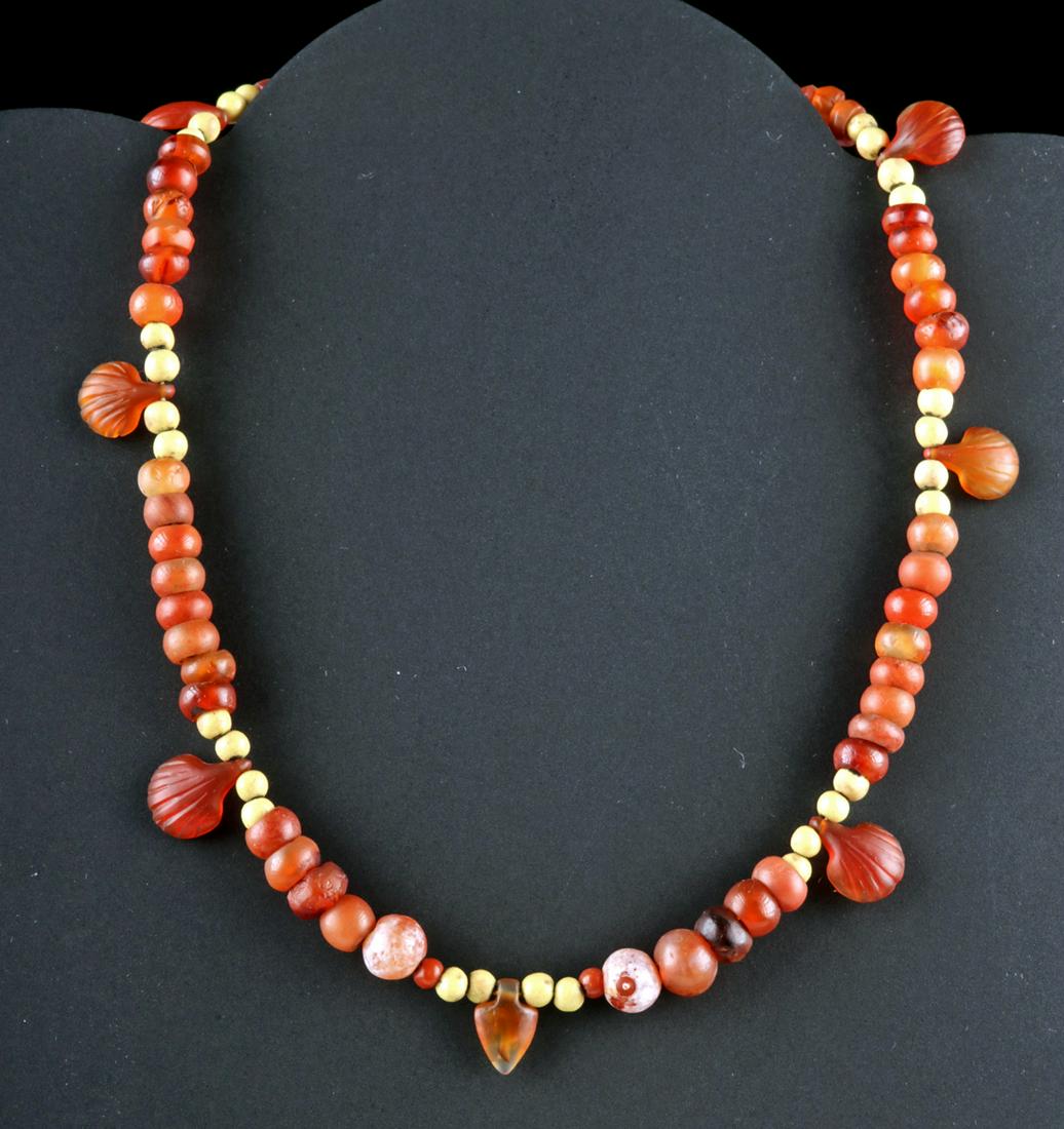Egyptian Jasper / Carnelian Necklace - Shell Amulets: Ancient Egypt, Late Dynastic period, ca. 712 to 332 BCE. A wearable necklace composed of ancient Egyptian carnelian and jasper seed beads and seven carnelian amulets. Six of these amulets are in the f