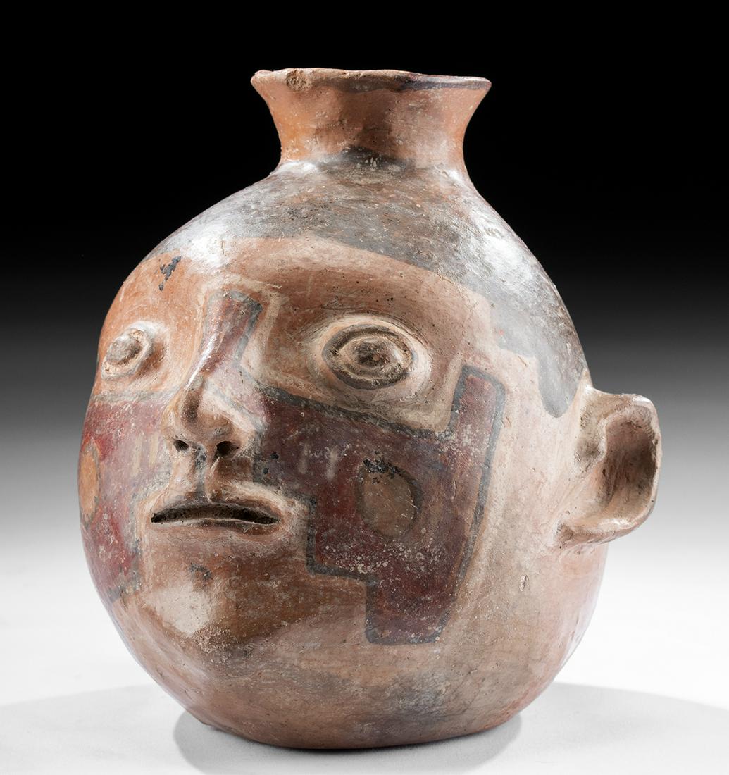 Fine Tiahuanaco Polychrome Portrait Vessel: Pre-Columbian, Bolivia and Chile, Tiahuanaco (Tiwanaku), ca. 400 to 700 CE. An intriguing example of a hand-built pottery vessel depicting a human head, perhaps a warrior or shaman based on the broad,