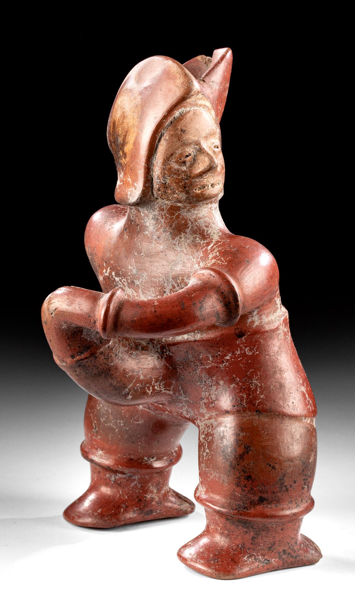 Colima Redware Vessel - Man Holding Huge Phallus: Pre-Columbian, West Mexico, Colima, ca. 300 BCE to 300 CE. A hand-built and highly burnished redware pottery figure standing atop delineated legs and broad feet. The man leans slightly forward while s