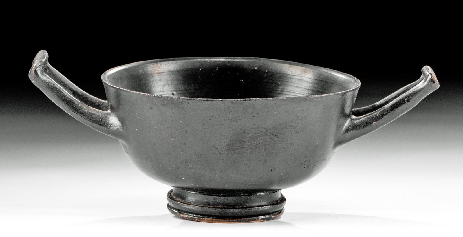 Greek Attic Blackware Skyphos / Deep Kylix: Ancient Greece, Athens (Attic), ca. 5th century BCE. A finely-executed blackware skyphos or deep kylix with a rounded body, standing upon a tiered ring base, with twin upraised loop handles on either 