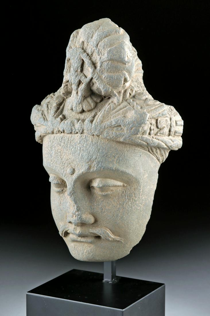 Gandharan Schist Head of Prince Siddhartha: **Originally Listed At $2200** Central Asia, Pakistan and Afghanistan, Gandharan Empire, ca. 200 BCE to 100 CE. An evocative hand-carved grey schist head of Buddha, presenting a sensitively modeled fa