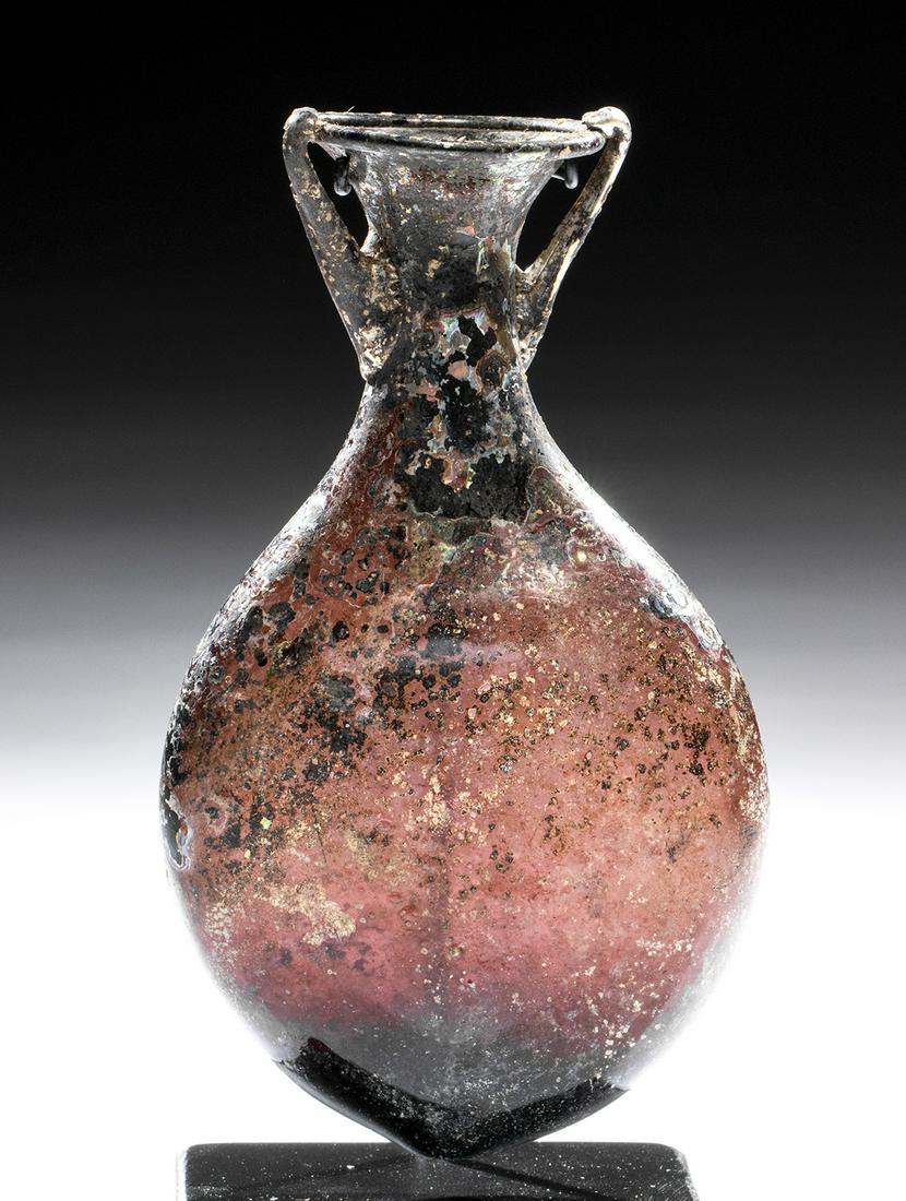 Roman Glass Pilgrim Flask - Aubergine & Iridescent!: Roman, Imperial Period, ca. 3rd to 4th century CE. A striking glass pilgrim flask created from stunning translucent aubergine glass that has developed marvelous silvery and rainbow iridescence. Its fo