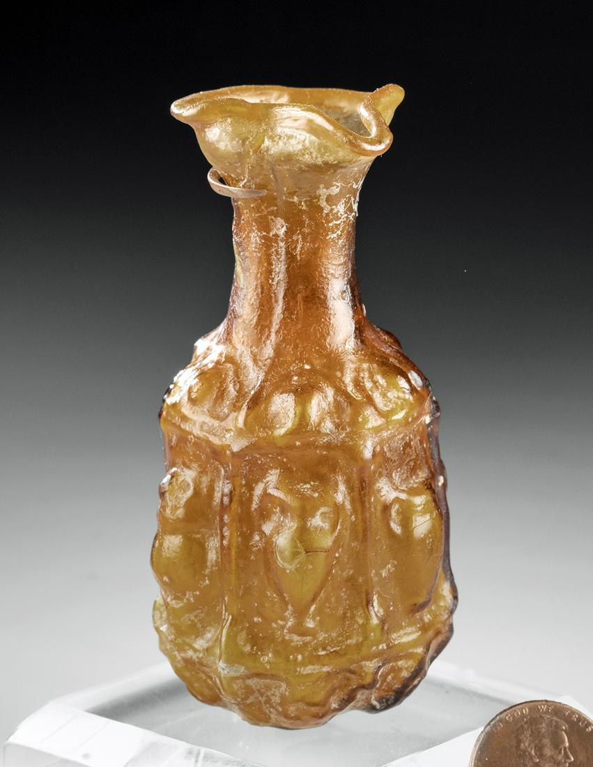 Gorgeous Roman Sidonian Glass Bottle Amphoras in Relief: Roman, Sidonian, ca. 2nd to 4th century CE. A stunning miniature mold-blown glass vessel, the globular body presenting 6 panels, each one adorned by an amphora in relief, with leaf forms adorning the 