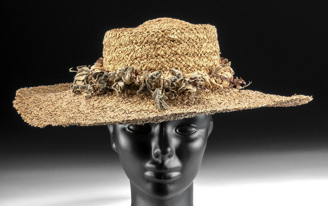 Early 20th C. Hawaiian Woven Hat by Hilo Hattie: South Pacific, Hawaiian Islands, ca. 1930s CE, made by the Hilo Hattie Company of Hawaii. A broad hat of a lightweight form woven from sturdy grass fibers and adorned with a woven flower band on top. 