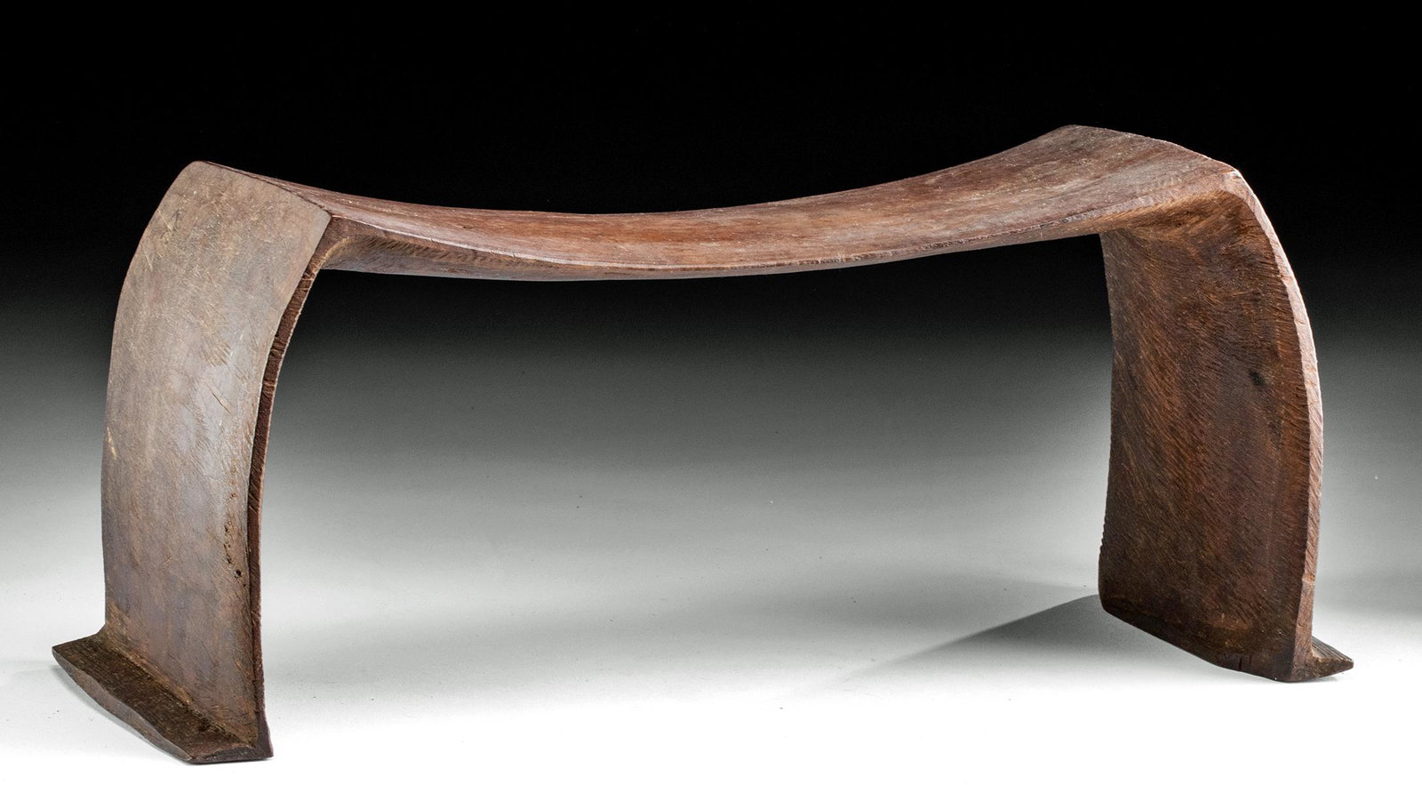 19th C. Fijian Lau Archipelago Wood Head Rest: Polynesia, Fiji, Lau Archipelago, 19th century CE. A hand-carved wooden headrest of an elegant Minimalist style, presenting a gently curved platform supported by two integral out-curved legs that seam