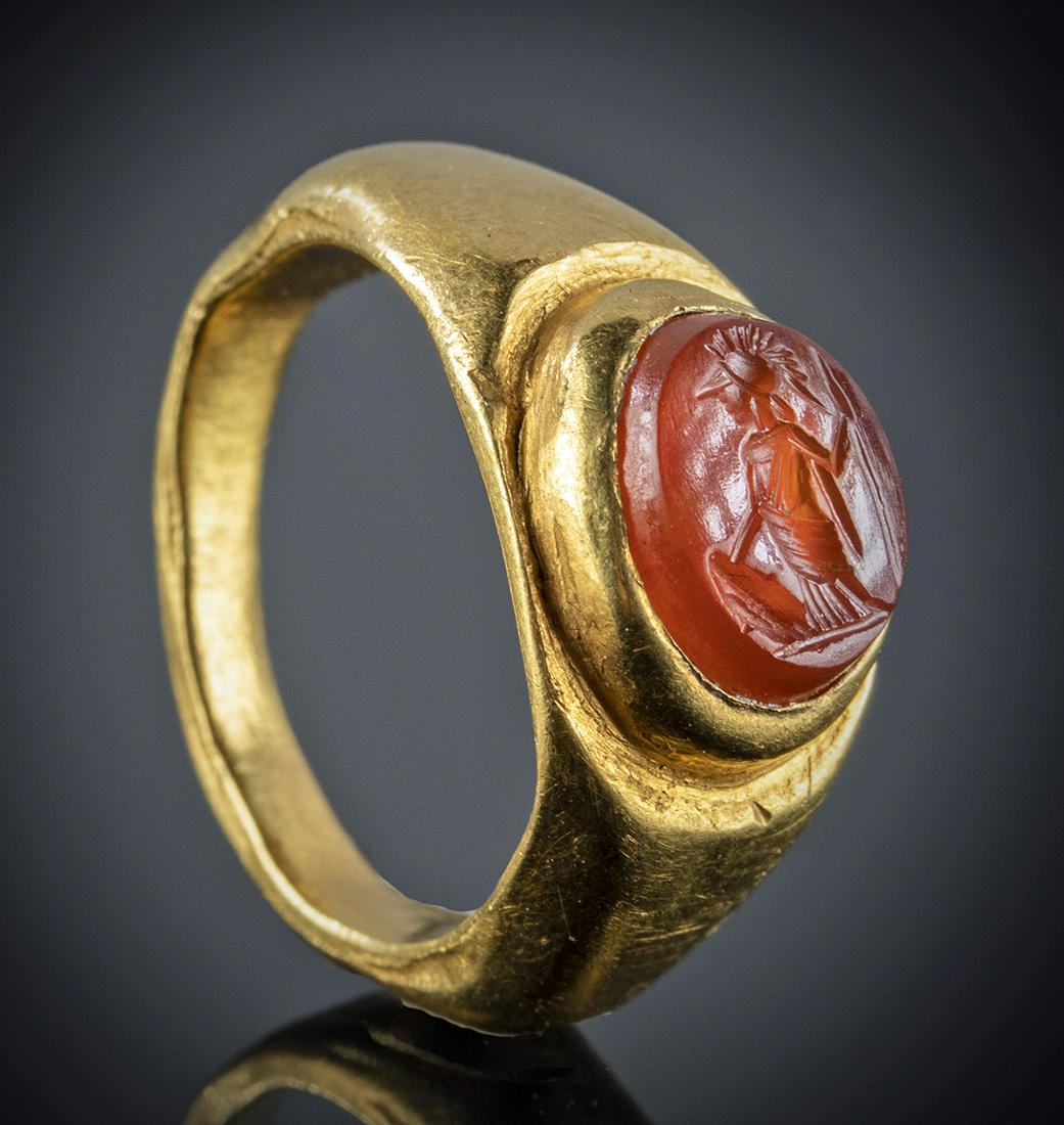 Roman 21K+ Gold Ring Carnelian Intaglio Minerva: Roman, Imperial Period, ca. 1st to 3rd century CE. A stunning 21K+ gold ring with a carnelian intaglio elegantly engraved with a profile image of Minerva (Greek Athena), the goddess of wisdom, war, ar