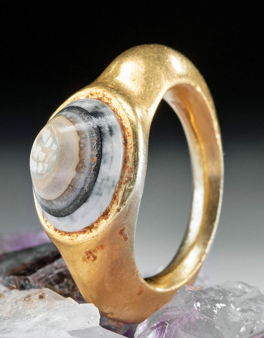 Lovely Roman 22K+ Gold Ring w/ Eye Agate Cabochon: Roman, Imperial Period, ca. 2nd to 4th century CE. A fine 22K+ gold ring (comprised of 94% gold) with a smooth, curved band adorned by an ovoid eye agate cabochon of banded cream, caramel brown, black