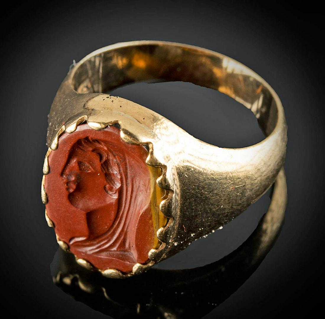 Roman 18K Gold Ring w/ Banded Red Jasper Intaglio: Roman, Imperial Period, ca. 1st to 3rd century CE. A lovely red and burnt orange banded jasper intaglio with a finely carved depiction of a youthful woman's head in profile. She has an unlined face, a