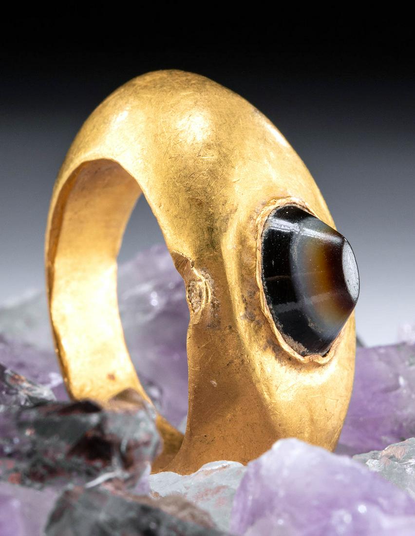 Roman 22K+ Gold Ring w/ Banded Agate: Roman, Imperial Period, ca. 2nd to 4th century CE. A fine 22K+ gold ring (comprised of 95% gold) with a smooth, curved band adorned by an ovoid eye agate cabochon of banded caramel brown and white hue
