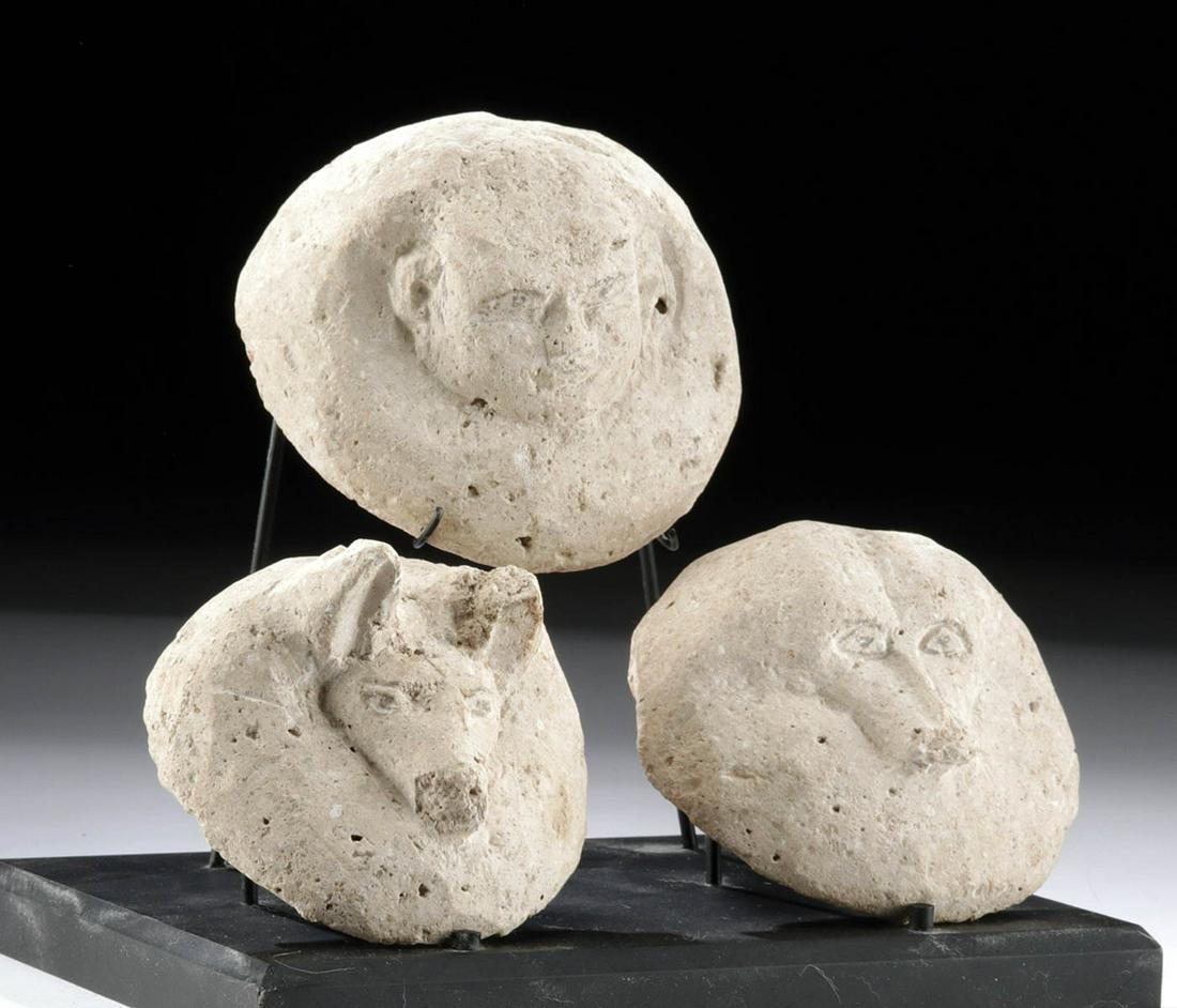 Egyptian 18th Dynasty Stone Canopic Jar Lids (3): Ancient Egypt, New Kingdom, 18th Dynasty, ca. 1479 to 1401 BCE. Wow! A trio of fascinating limestone lids from canopic jars, all displayed together on a custom stand. Each lid is rounded, and bears th
