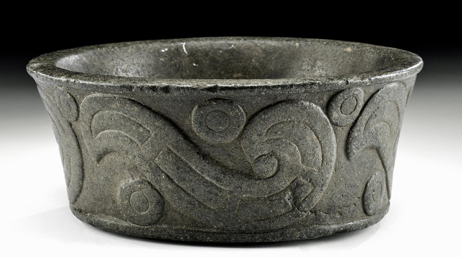 Very Fine Decorated Mapuche Stone Bowl: Pre-Columbian, northern Chile or Argentina, Mapuche people, ca. 1500 CE. Finely carved from a single piece of hard black/brown basalt and polished to have a smooth surface on the interior, raised desi