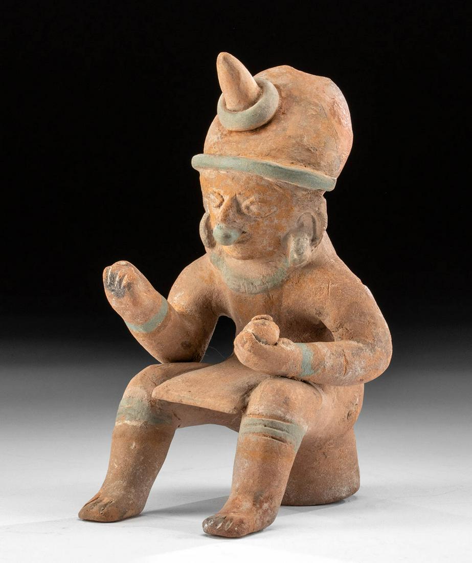 Jamacoaque Polychrome Seated Shaman Figure: Pre-Columbian, Ecuador, Jamacoaque culture (also Jama Coaque), ca. 0 to 500 CE. A skillfully hand-built, modeled, and beautifully painted shaman figure who sits upon a stool or drum and holds a mortar