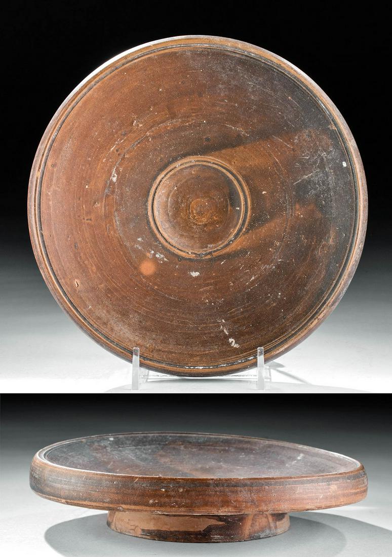 Greek South Italic Redware Fish Plate: Magna Graecia, South Italic colonies, Apulia or Campania, ca. 360 to 325 BCE. A simple yet elegant wheel-thrown ceramic plate with a squat footed base, a wide upper surface with an overhanging rim, an