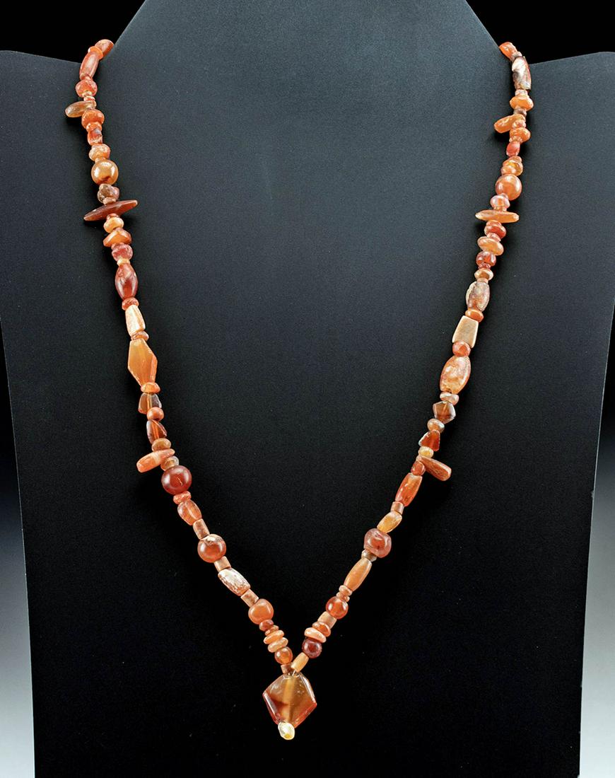 Roman Carnelian Bead Necklace: Roman, Imperial Period, ca. 1st to 3rd century CE. A gorgeous necklace constructed with dozens of petite carnelian beads of warm vermilion and citrine hues. The necklace features beads in spherical, t