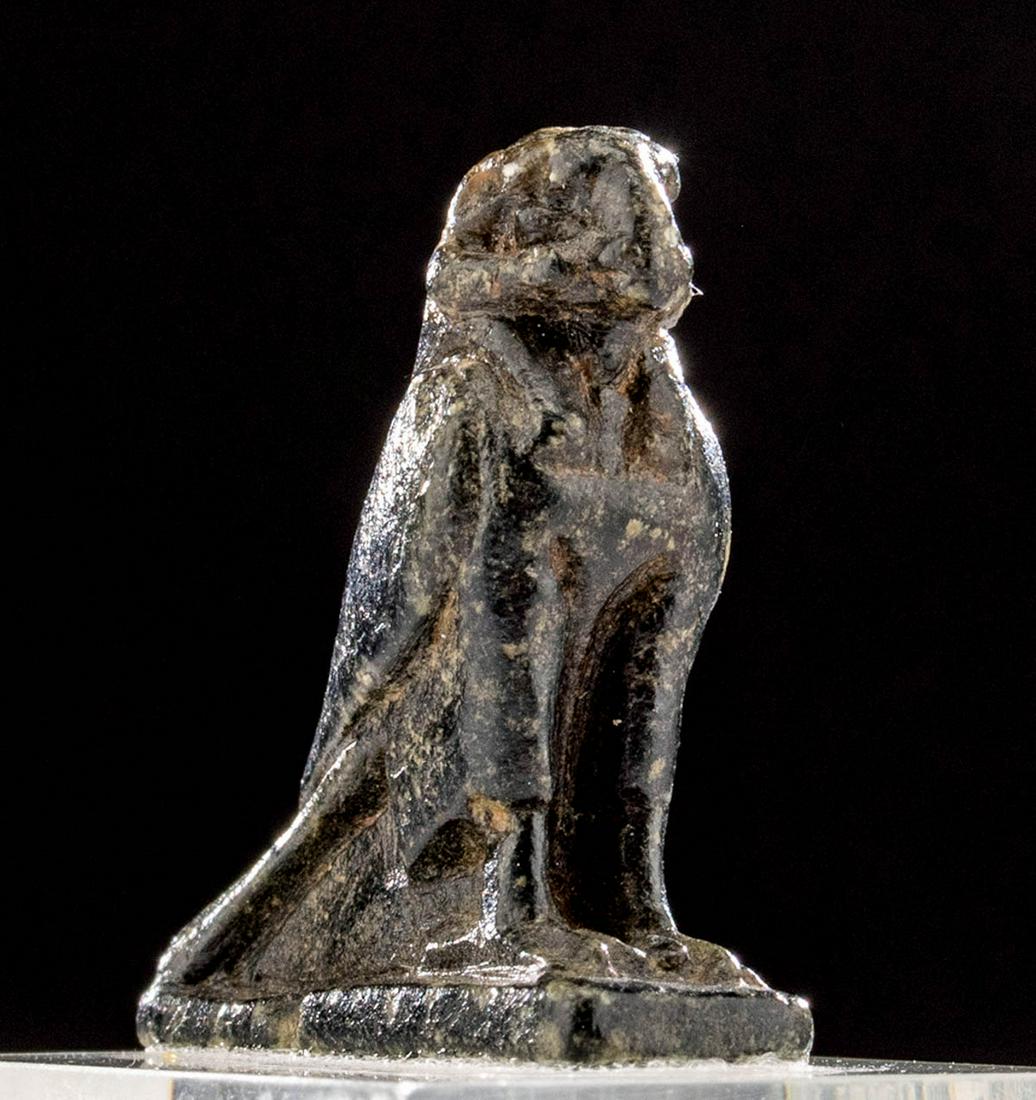 Exhibited Egyptian Steatite Amulet, Ram-Headed Falcon: Ancient Egypt, New Kingdom to Ptolemaic Period, ca. 1550 to 30 BCE. An intriguing amulet carved from mottled steatite in the form of a ram-headed falcon. The petite bird stands atop slender legs and f