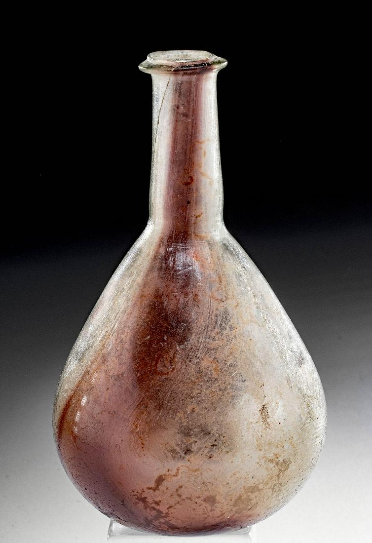 Roman Glass Flask w/ Aubergine Streak: Roman, early Imperial Period, ca. 1st to first half of 2nd century CE. An attractive flask that is free-blown from semi-translucent glass of a pale yellow-green color that exhibits an integral, vertic