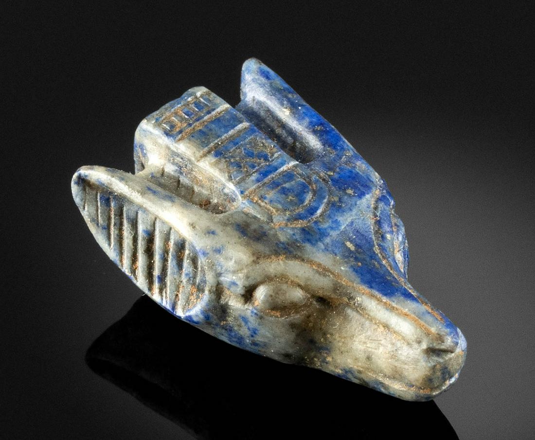 Rare Egyptian Lapis Lazuli Canid Head Pendant: Egypt, Ptolemaic period to early Coptic culture, ca. late 4th century BCE to 3rd century CE. A beautiful pendant carved from blue and white lapis lazuli depicting the head of a canid, perhaps a jackal