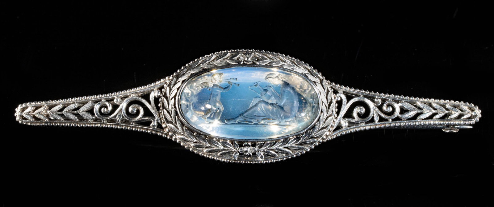 Fine Neoclassical Platinum Brooch & Moonstone Intaglio: Western Europe, probably England or France, Neoclassical Period, ca. 18th to early 19th century CE. A stunning brooch of an openwork platinum design that exhibits an ovoid body flanked by a pair of na