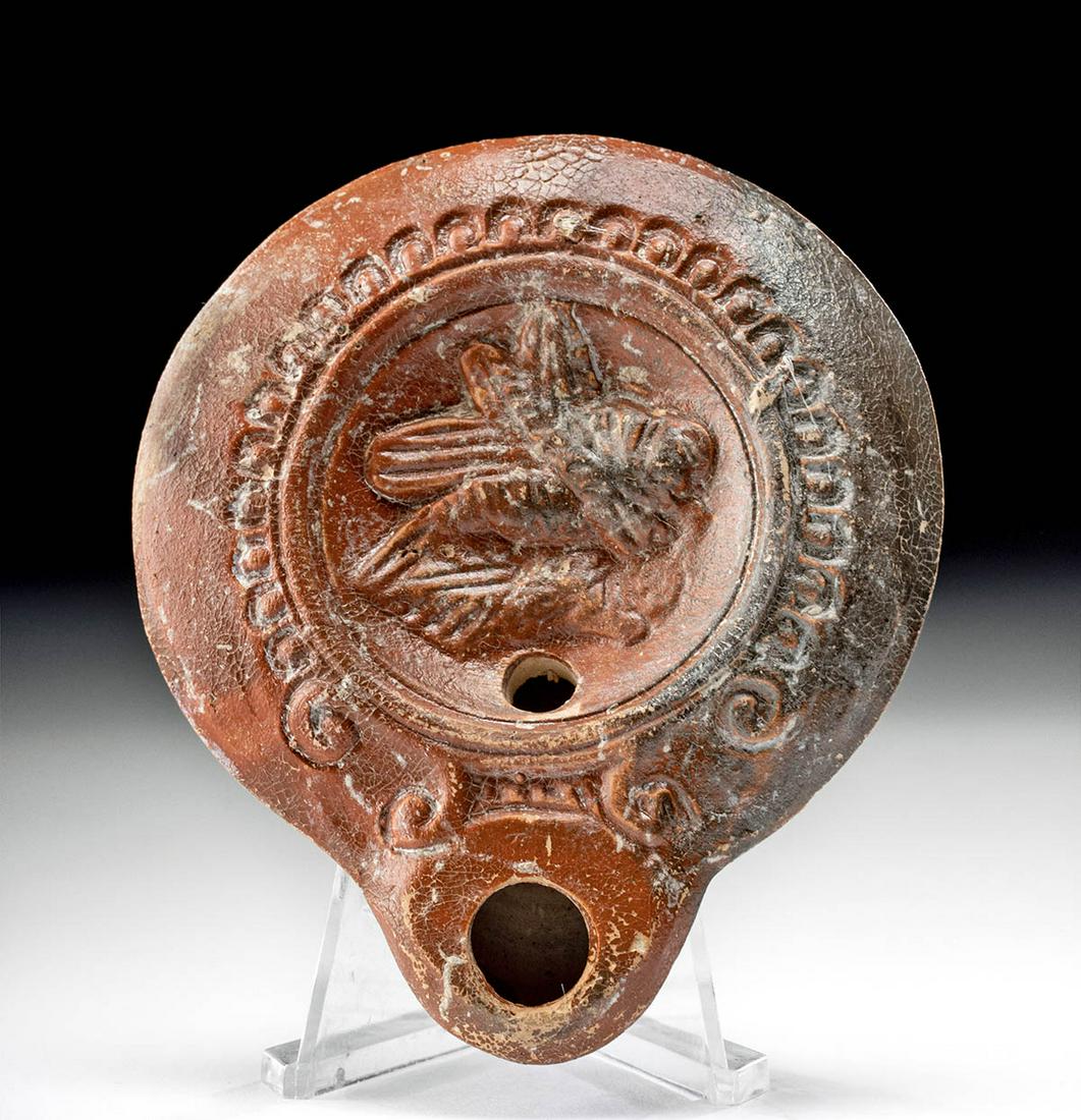 Roman Pottery Oil Lamp w/ Grasshopper: Roman, Imperial Period, ca. 1st to 3rd century CE. This beautiful mold-formed oil lamp with sienna color glaze sits upon a flattened base with five concentric circles of a bullseye design. The wide wa