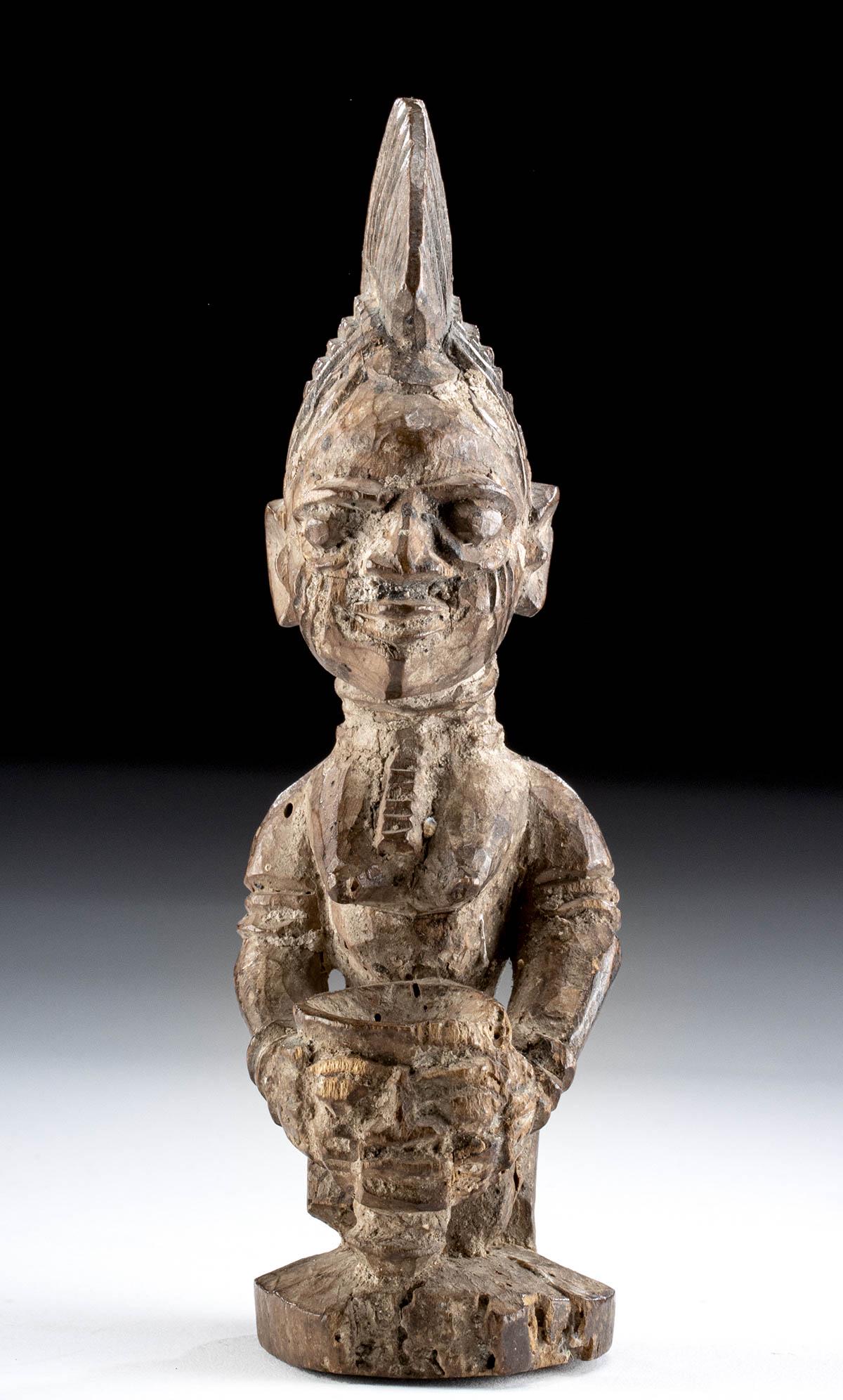 20th C. African Yoruba Wood Female Ibeji, ex-Christie's: **First Time At Auction** West Africa, Nigeria, Yoruba, ca. early to mid-20th century CE. A hand-carved wooden female ibeji figure kneeling atop an integral plinth. The nude woman holds a small jar in