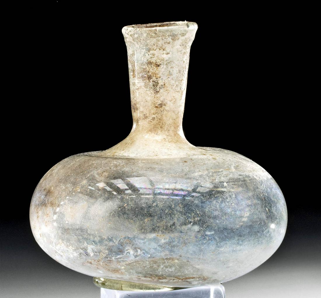 Roman Glass Flask w/ Iridescence: Roman, Imperial Period, ca. 2nd to 3rd century CE. A fabulous free-blown and intact translucent glass flask! The vessel sits upon a ring base with a slightly concave bottom, presents with a flattened