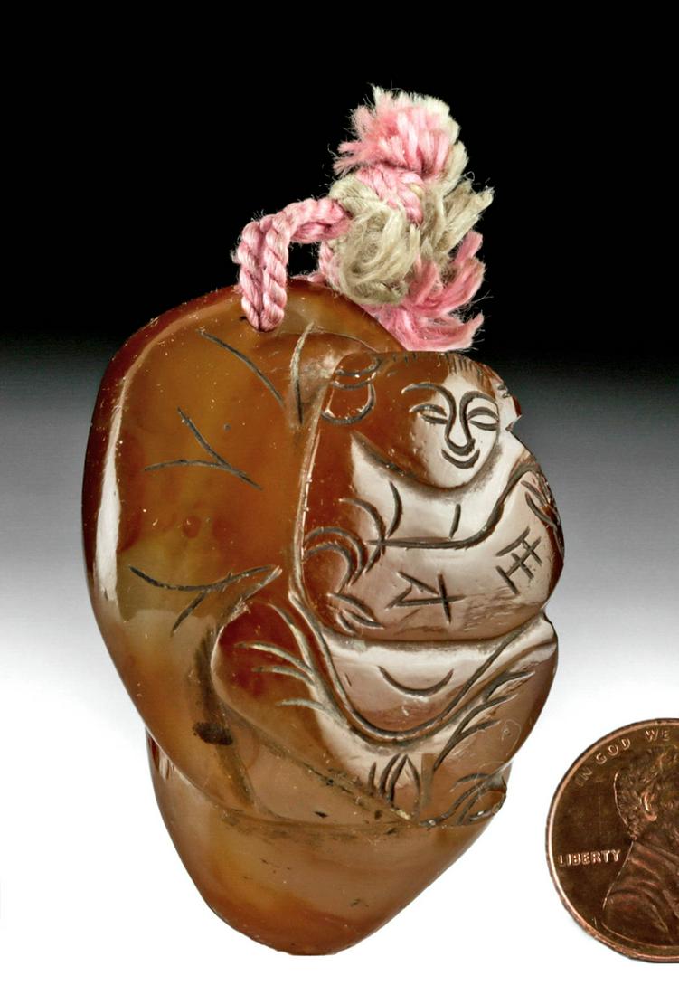 20th C. Chinese Qing Brown Quartz Amulet: East Asia, China, late Qing to Republic period, ca. early 20th century CE. A translucent brown quartz amulet, carved and smoothed to incorporate the natural shape of the stone, with a smiling older wo