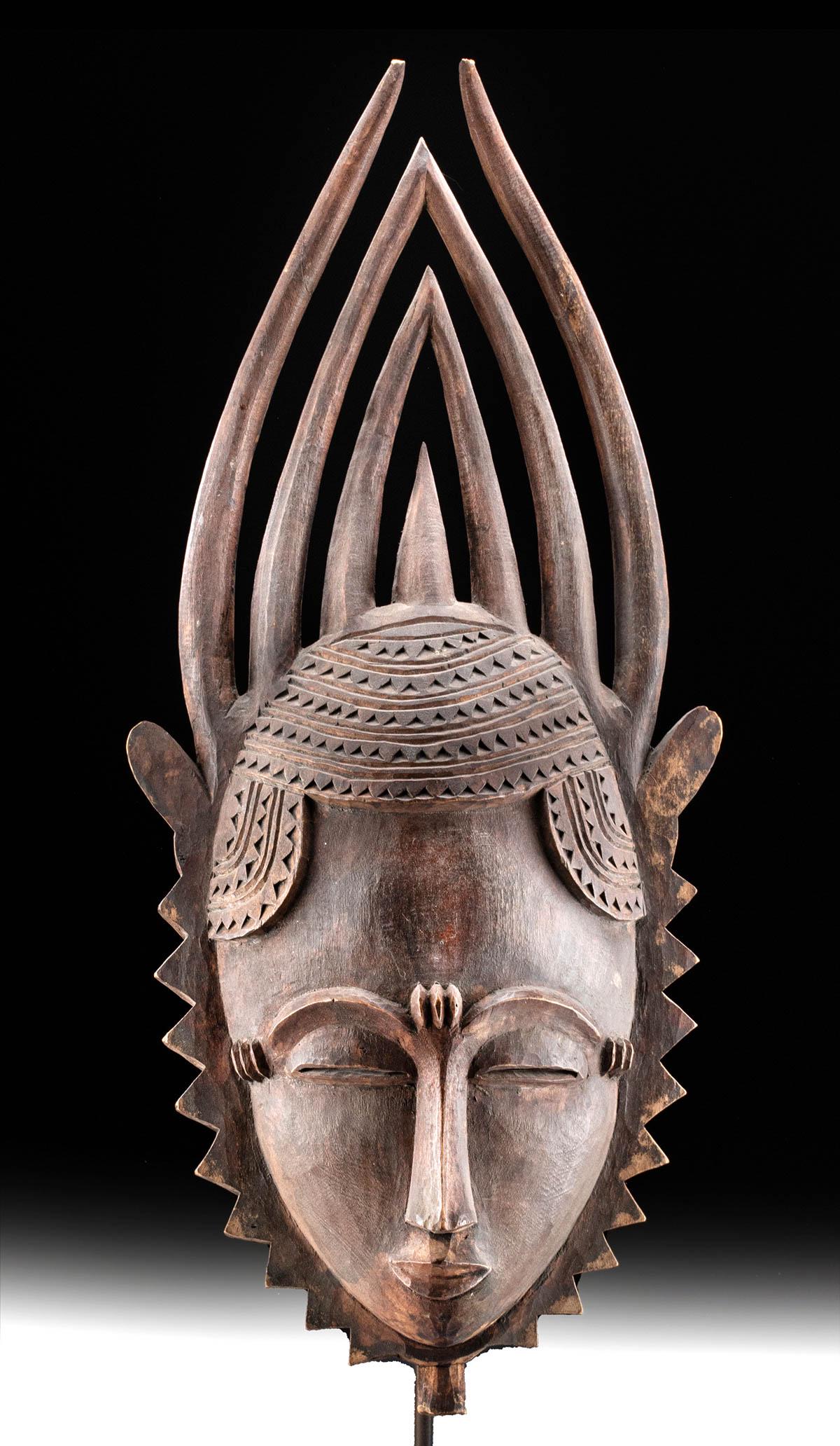 Early 20th C. African Yaure Wooden Face Mask: West Africa, Ivory Coast, Yaure (also Yaoure, Yohure) peoples, ca. early to mid-20th century CE. Finely carved from deep brown wood, this is an expressive face mask with intricate features and a massi