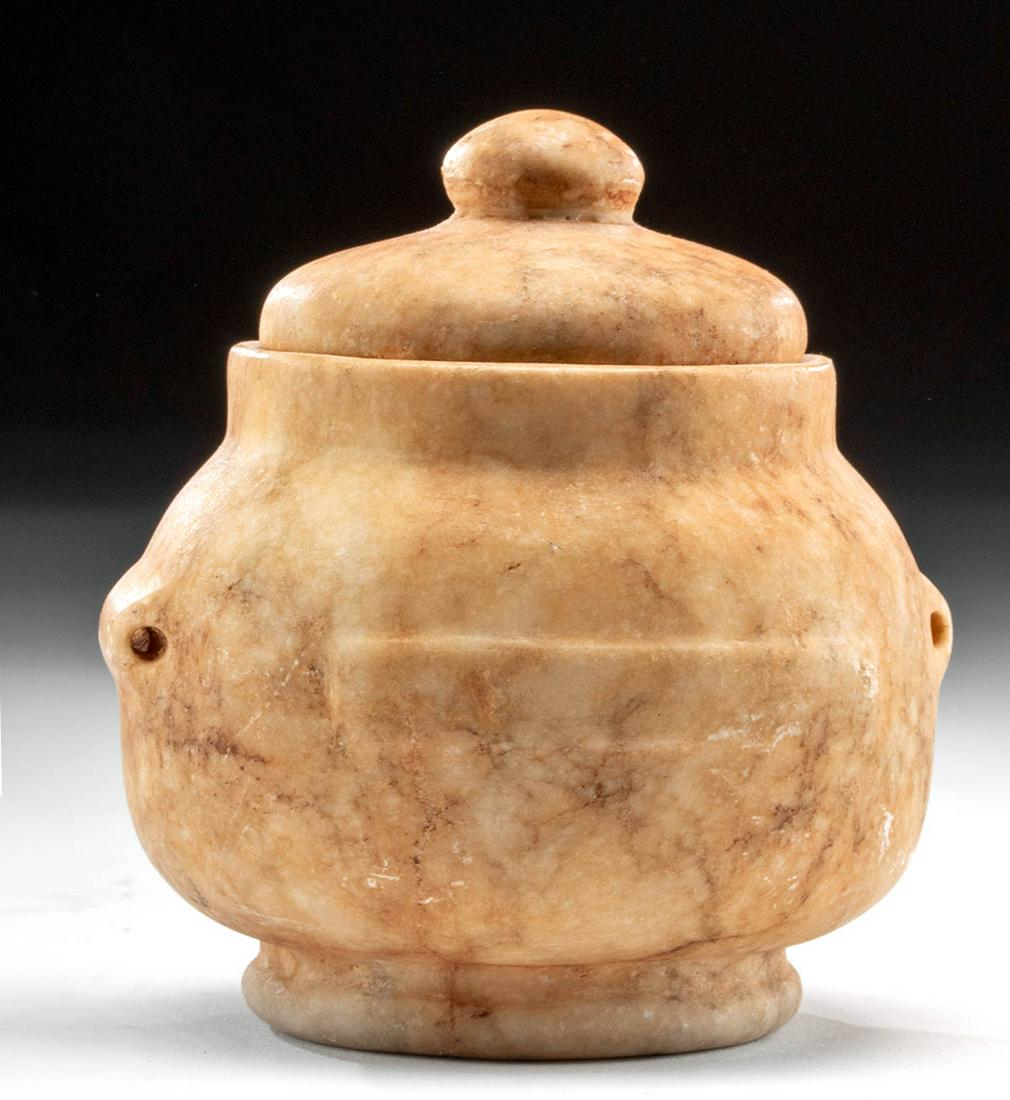 Egyptian Alabaster Jar with Lid: Egypt, Late Dynastic Period, 26th to 31st Dynasty, ca. 664 to 332 BCE. A sizable jar, hand-carved from a creamy white alabaster with darker banded inclusions. The piriform body rests upon a disc-shape