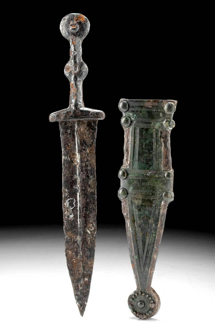 Roman Steel Pugio Dagger w/ Ornate Bronze Scabbard: Roman, Imperial Period, ca. 1st to 2nd century CE. A handsome cast steel short dagger, known as a pugio with an ornate bronze and steel scabbard. The pugio has a short handle, a round pommel and midse