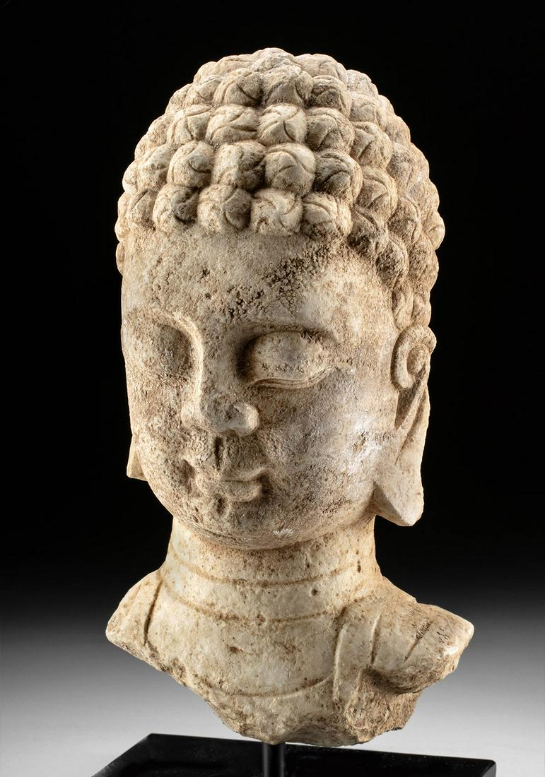 Chinese Ming Dynasty Stone Buddha Head Fragment: East Asia, China, Ming Dynasty, ca. 1368 to 1644 CE. A sensitively hand carved Buddha head, a piece from a larger sculpture that perhaps resided in a shrine or temple. The visage is serene, the eyes c