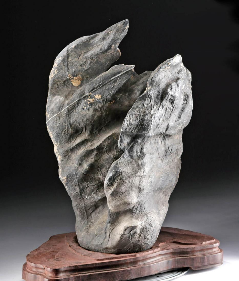 Chinese Qing Dynasty Scholar's Stone + Wood Base: East Asia, China, Qing Dynasty, ca. 17th to 18th century CE. An evocative "gongshi", a scholar's rock or scholar's stone, this example a naturally formed piece of black limestone that stands tall and