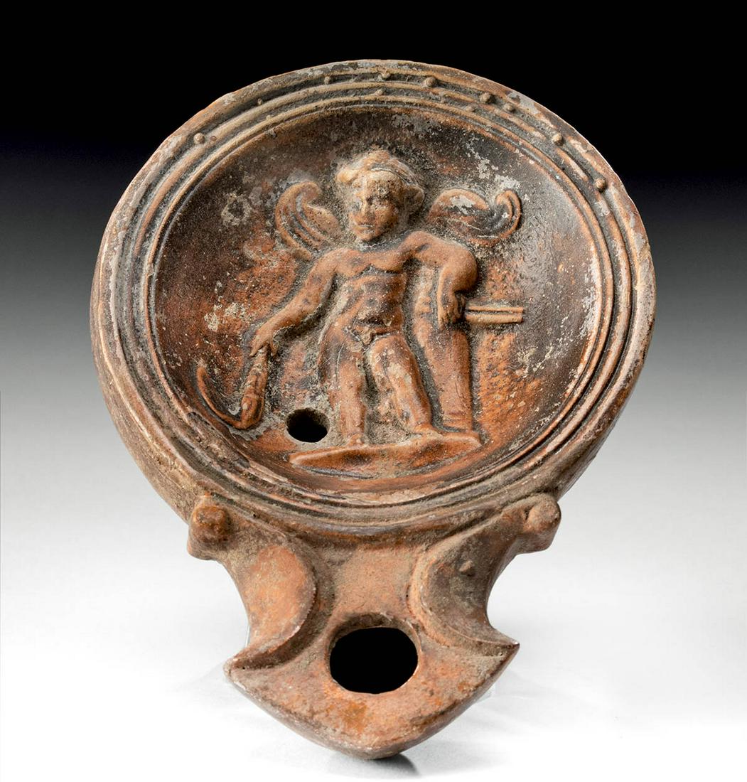 Charming Roman Pottery Oil Lamp Cupid / Eros: Rome, Imperial, ca. 2nd to 4th century CE. A charming mold-formed pottery oil lamp featuring a circular base that rises to rounded walls, a concave central relief tondo, a petite fill hole, and a wide