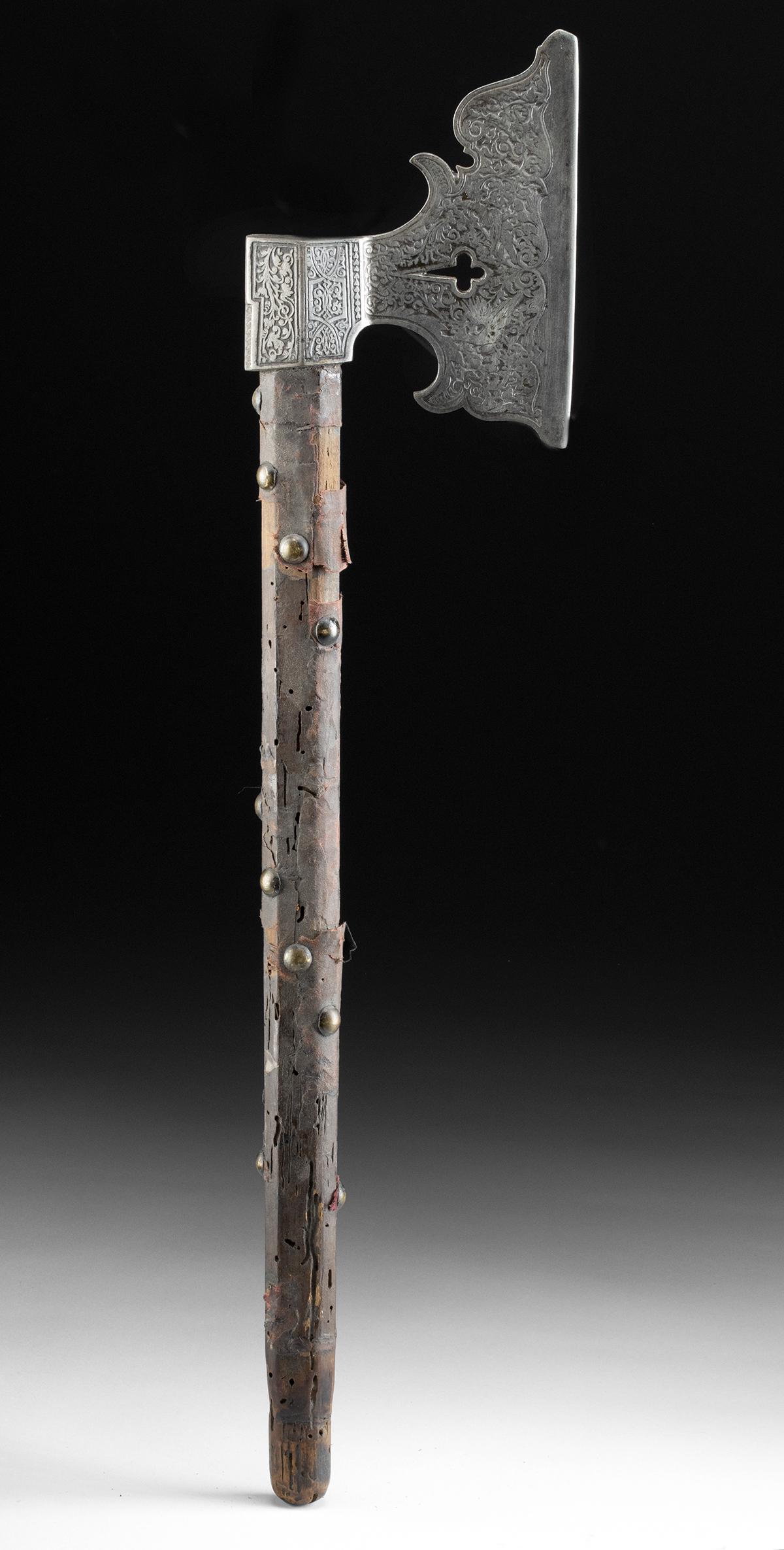 20th C. European Etched Iron Axe Head Wood Handle: Europe, ca. early to mid 20th century CE. Iron axe head designed to channel the spirit of the Middle Ages, its flourish-shaped surface decorated with relief floral motifs. With a wooden handle studded