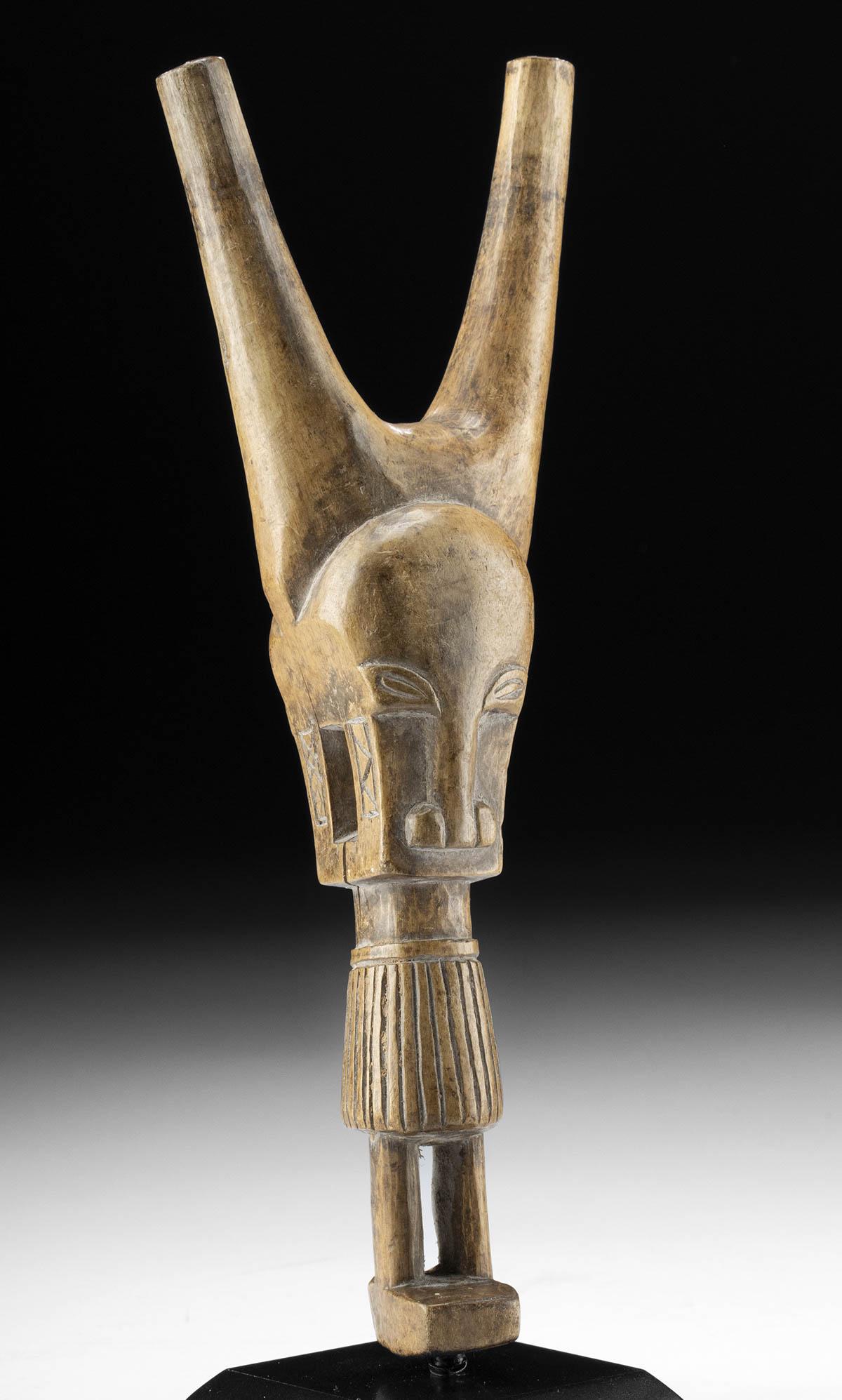 20th C. African Baule Wood Slingshot Handle Janus-Head: Western Africa, Ivory Coast, Baule (Baoule) people, ca. mid 20th century CE. A delightful wooden slingshot handle in the form of a janus-headed, somewhat anthropomorphized antelope with an oversized h