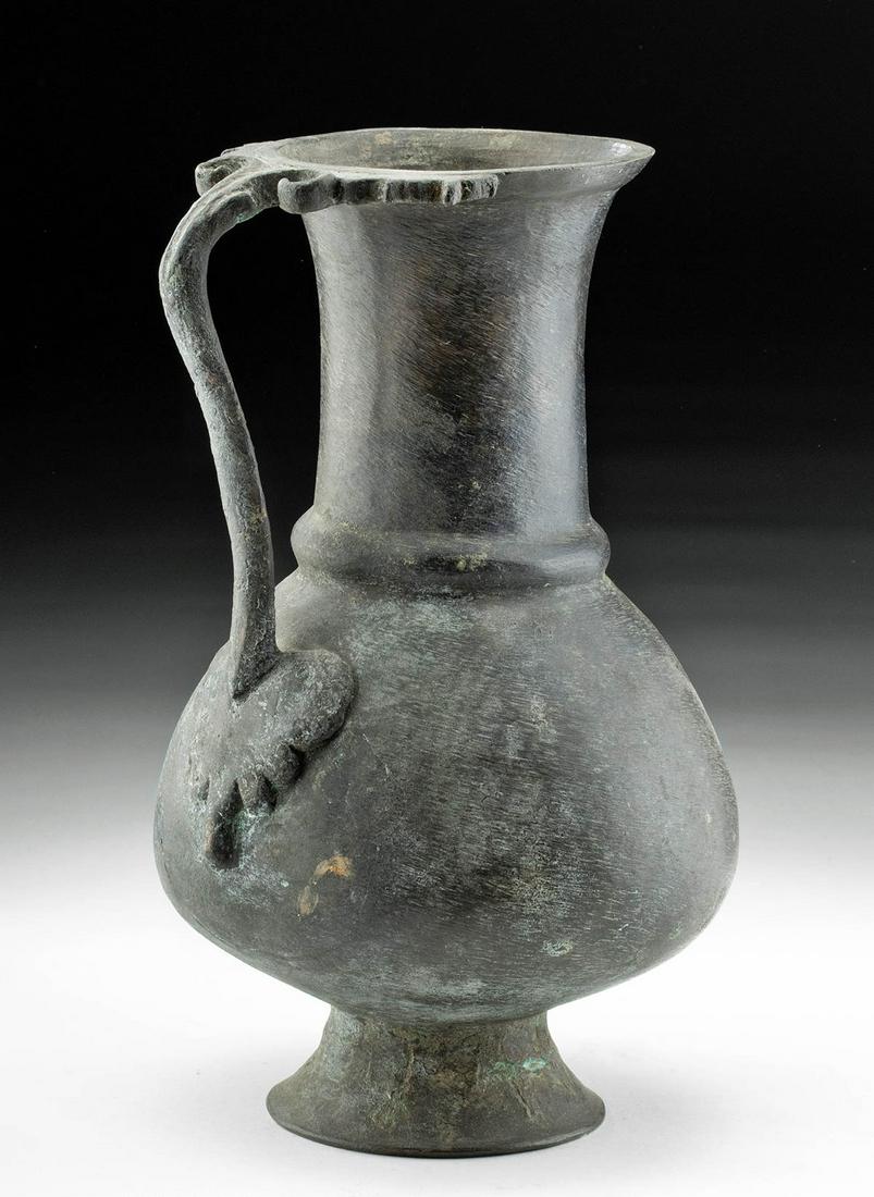 Roman Bronze Pitcher w/ Grape Leaf Handle: Roman, Imperial Period, ca. 1st to 4th century CE. A cast bronze pitcher that rests elegantly on a concave foot. The globular body has a nice grape leaf applique adorning the base of the handle, and t