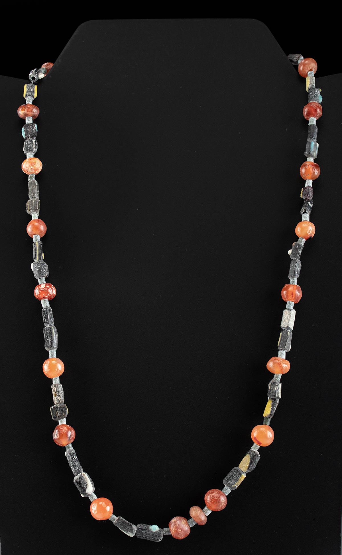 Roman Carnelian & Glass Bead Necklace: Roman, Imperial Period, ca. 1st to 4th century CE. A gorgeous wearable necklace with 21 spherical and oblate carnelian beads in hues of coral, cerise, and burgundy organized in a pattern with each sep