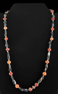 Roman Carnelian & Glass Bead Necklace: Roman, Imperial Period, ca. 1st to 4th century CE. A gorgeous wearable necklace with 21 spherical and oblate carnelian beads in hues of coral, cerise, and burgundy organized in a pattern with each