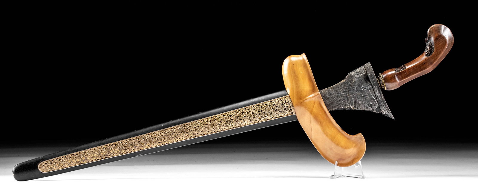 Mid-20th C. Indonesian Steel Kris w/ Gilt Copper: Southeast Asia, Indonesia, ca. mid-20th century CE. A fine ceremonial kris (also keris) of a dignified style. The hand-carved wooden handle displays a pair of abstract anthropomorphic maskettes along 