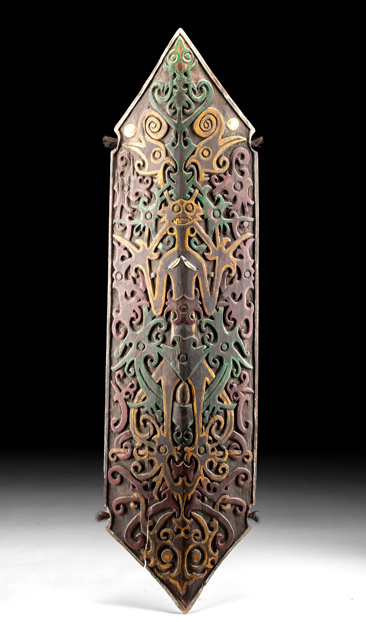 19th C. Indonesian Dayak Polychrome Wood Shield: Indonesia, Borneo, Central Kalimantan, Dayak peoples, ca. late 19th to early 20th century CE. A tall hexagonal wooden shield with pointed tips and intricately carved, symmetrical motifs of scrolling a