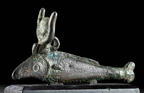 Exhibited Egyptian Bronze Oxyrhynchus Fish: Egypt, Late Period to Ptolemaic, ca. 664 to 30 BCE. A cast leaded bronze oxyrhynchus fish figurine, wearing a crown with horns, solar disk, and uraeus, its body embellished with incised scales as