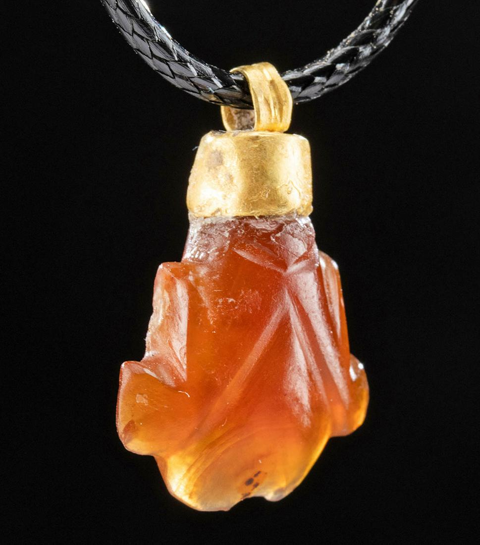Roman Gold and Carnelian Frog Pendant: Egypt, Roman, ca. 1st to 3rd century CE. A lovely frog pendant comprised of a carnelian stone, the amphibian carved as an abstract, symmetrical, crest-like form with curved and angular features and an